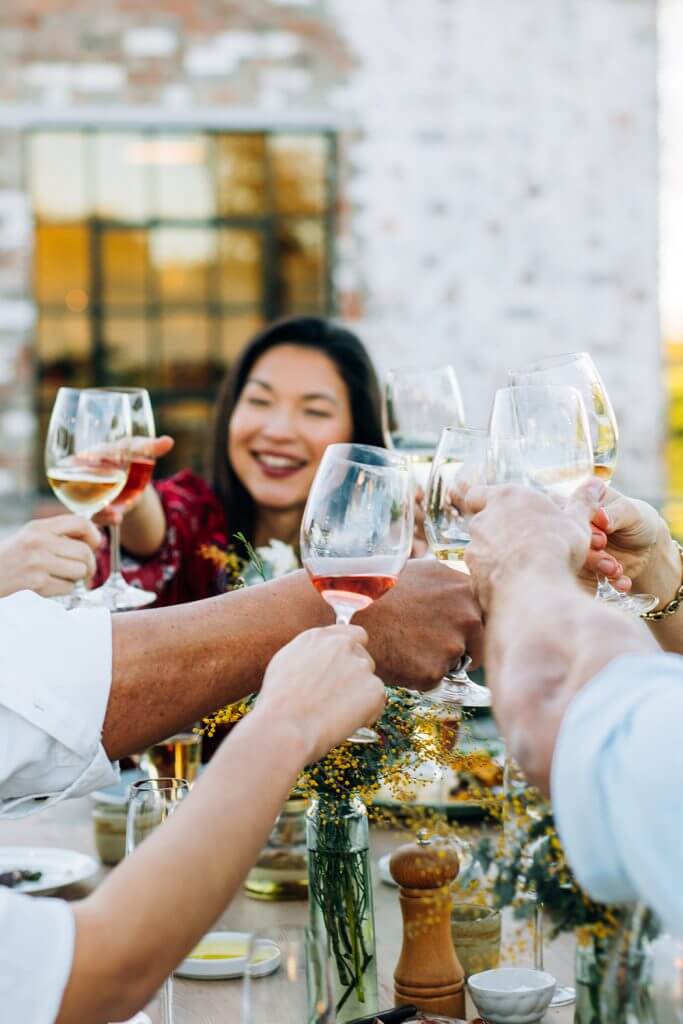 A group of community residents make a toast with wine in glasses during brunch.